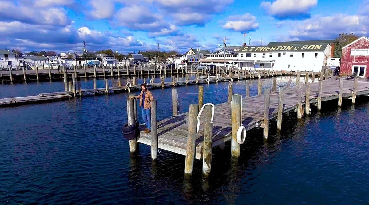 Man standing at the edge of Greenport dock right by the water